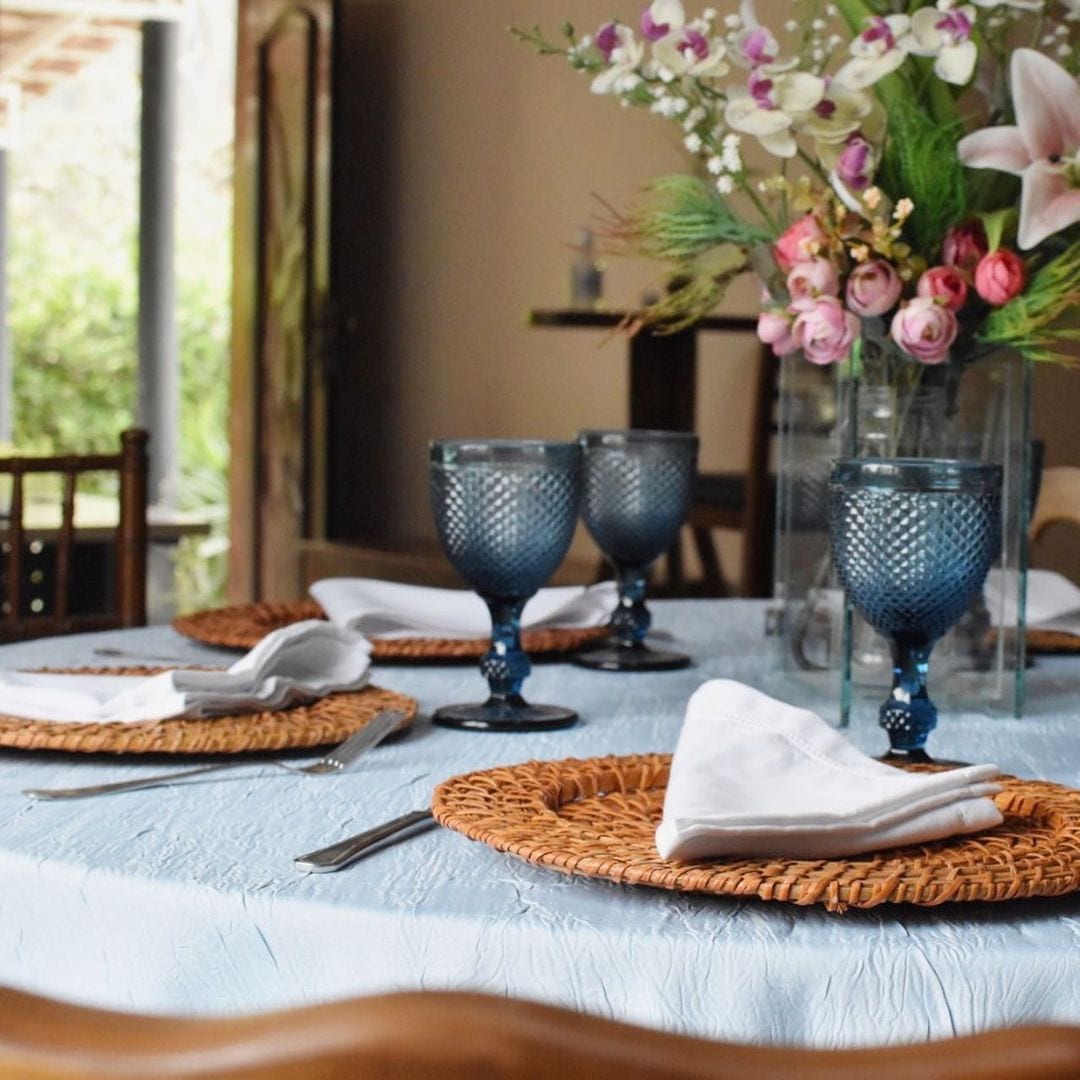 Mesa posta com taças azuis e sousplat de rattan